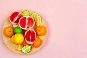 Bowl of citrus fruits on bright color background, flat lay, top view
