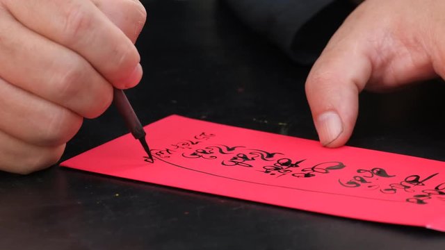 Vietnamese scholar write calligraphy at lunar new year. Calligraphy festival is a popular tradition during Vietnam Tet holiday. Calligrapher draw handwriting in penmanship at fair in springtime