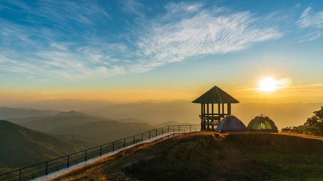 Picnic tent beside the pavilion on view point and high mountains. The sun is falling amidst many mountains. Concepts of tourism and adventure.