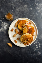 Concept of american breakfast with pancakes with caramel cream and nuts on dark background