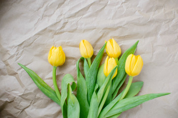 Bouquet of yellow tulips on wrapping paper. Valentine's Day and Mother's Day background. Top view Copy Space.