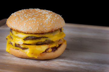 hamburger with cheese on a wood table with black background