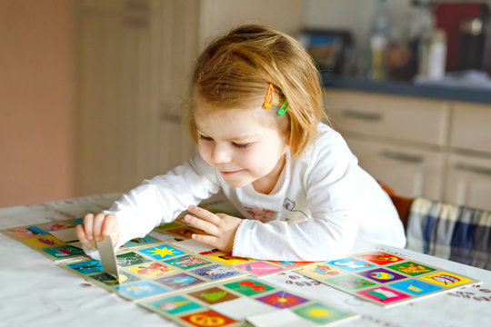 Adorable cute toddler girl playing picture card game at home or nursery. Happy healthy child training memory, thinking. Development step and education of kid.
