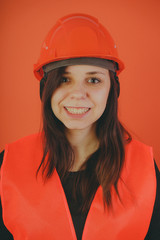 Girl construction worker, road worker or longshoreman, a woman in a helmet and orange vest