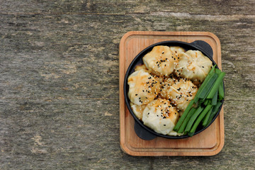 Chinese dumplings with soy sauce, green onions and sesame in a cast iron skillet. Dumplings in the Chinese style in a griddle.