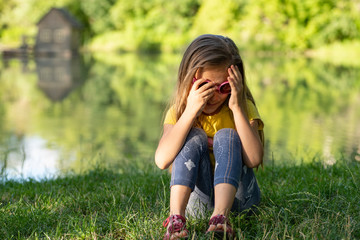 Little girl sitting alone and thinking about something ,The girl is sad on the river bank, on a...
