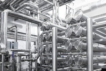 Steel water pipeline, chrome pipes, pipe lines in plant workshop. Industrial background
