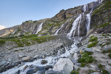 Fototapeta na wymiar Waterfall in the Caucasus mountains, melting glacier ridge Arkhyz, Sofia waterfalls. Beautiful high mountains of Russia, the river of pure ice water. Summer in the mountains, hike