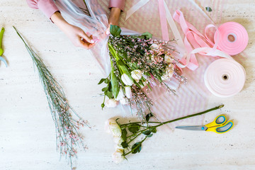 top view of female florist wrapping bouquet with tulips and roses on table