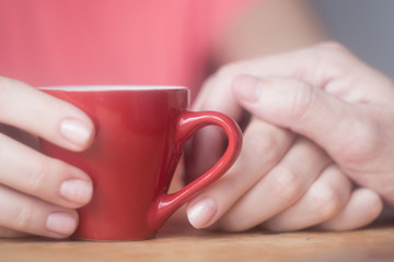 male hand touches female hand with a cup of coffee flirting, courting, love