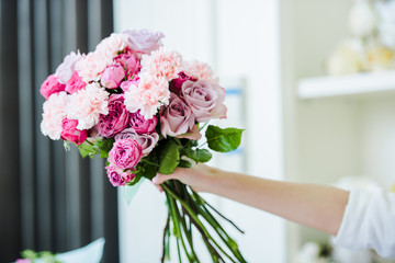 cropped view of woman holding pink bouquet of roses and carnations in hand