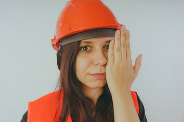 Girl construction worker, road worker or longshoreman, a woman in a helmet and orange vest