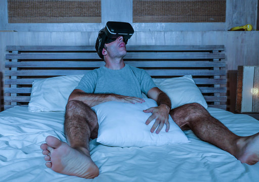 Fototapeta young excited and aroused man at home wearing 3d virtual realty goggles having fun on bed playing alone with internet cyber sex VR simulator in sexual illusion and desire