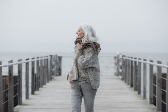 mature woman with long grey hair on a pier
