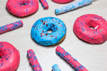 Delicious glazed donuts with sprinkles and candy sticks on light background
