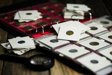 album with ukrainian coins and magnifier, numismatics on old wooden background