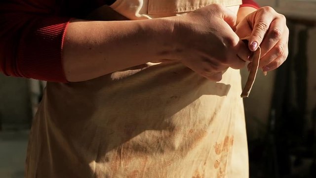 Close-up woman ceramist potter tieing apron before working with clay