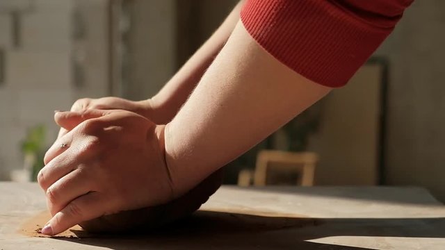 Panning close-up shot of female hands mixing clay ball monkey style