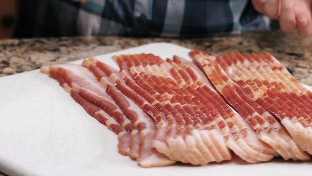 Bacon Slices On A Rotating Board. Close up shot of raw uncooked bacon strips on rotating chopping board.