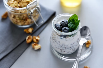 Chia seed pudding with granola, blueberry, walnut and honey decorated mint leaves on gray background. Selective focus. Healthy eating or vegetarian food concept