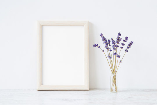 Dried purple lavender in vase on shelf at light gray wall. Mockup for positive idea. Empty place for inspirational, emotional, sentimental text, quote, sayings or photo in white frame. Front view. 