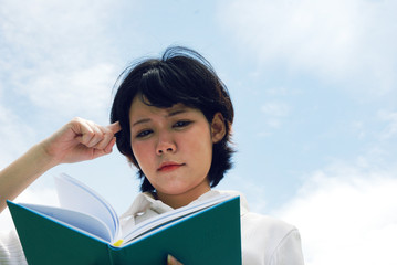 Obraz premium Beautiful woman reading and holding book on sky background.