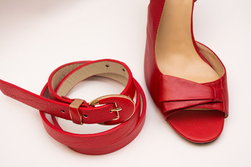 Red leather belt and women's red shoes on a white background.