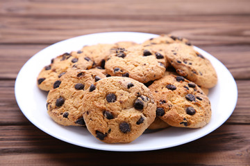 Chocolate chip cookies on plate on brown wooden background