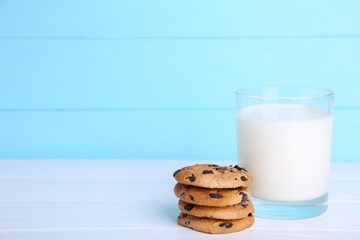 Glass of milk and chocolate cookies on blue background