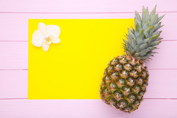 Ripe pineapple with orchid on a pink background with copy space
