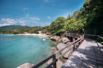 Fototapeta premium Tropical landscape with rocky beach and wooden bridge