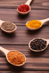 Spices mix on wooden spoons on a brown wooden background. Top view
