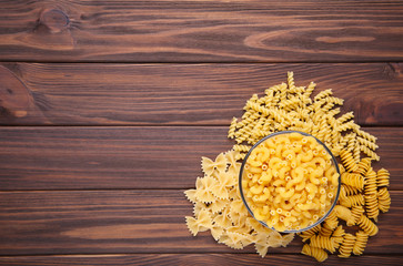 Delicious mixed pasta in bowl on a brown background
