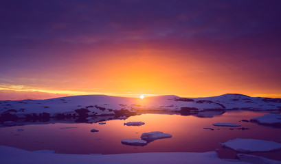 Colorful cloudy sky over the Antarctica shoreline Bay. Overwhelming sunset view. The snow covered shore next to the cold ocean. Ideal background for the collages in blue, purple and orange tints. - obrazy, fototapety, plakaty