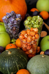 Green, purple and orange colored popcorn and fruit mix on a dark background