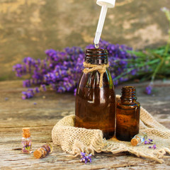 Lavender oil in different bottles on wooden background.