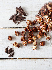 Chocolate popcorn and pieces of chocolate on a wooden table