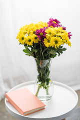 Fresh flowers and book on white table