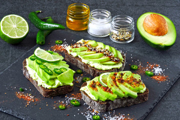 Beautifully plated avocado toast with delicious-looking toppings. Healthy Avocado Toasts on a Gray Stone Board.
