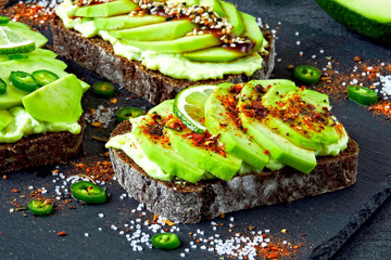 Beautifully plated avocado toast with delicious-looking toppings. Healthy Avocado Toasts on a Gray Stone Board.