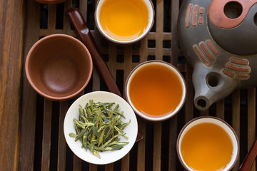 Authentic Chinese tea ceremony setting. Freshly brewed beverage poured in cups pot utensils on wooden tray. Loose tea leaves. Lifestyle local culture. Wellness balance buddhist meditation