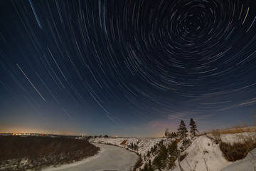 Star trail around the pole star in the night sky. Winter landscape photographed under the full moon.