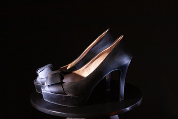 Black ladies stiletto heel pump with bow on black background.
