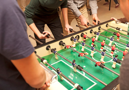 Guys are  playing table soccer indoor