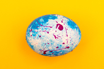 Blue handmade Easter egg on a yellow background. Religious traditional holiday.