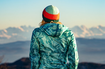 Junge Frau mit Mütze auf die Alpen blickend