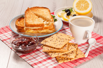 Toasted slices of bread with cheese, cookies, jam and cup of coffee.