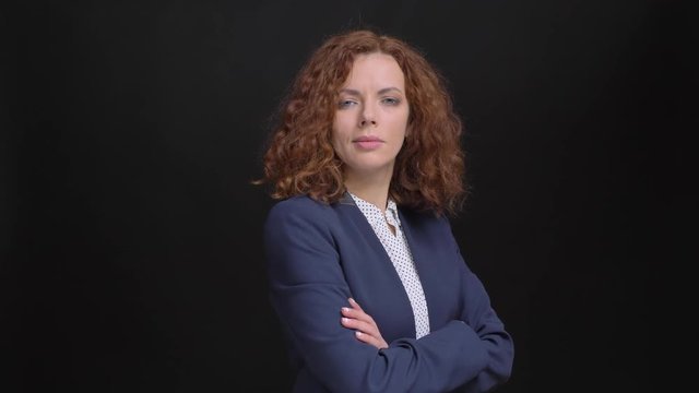 Closeup portrait of adult confident caucasian businesswoman looking at camera and having her arms crossed over chest