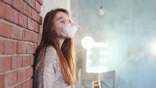 Sexy girl smokes vape.
