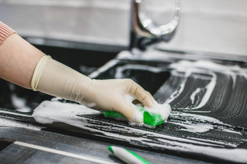 cleaning the sink from the ceramic coating of artificial stone with a foam agent in gloves. kitchen cleaning